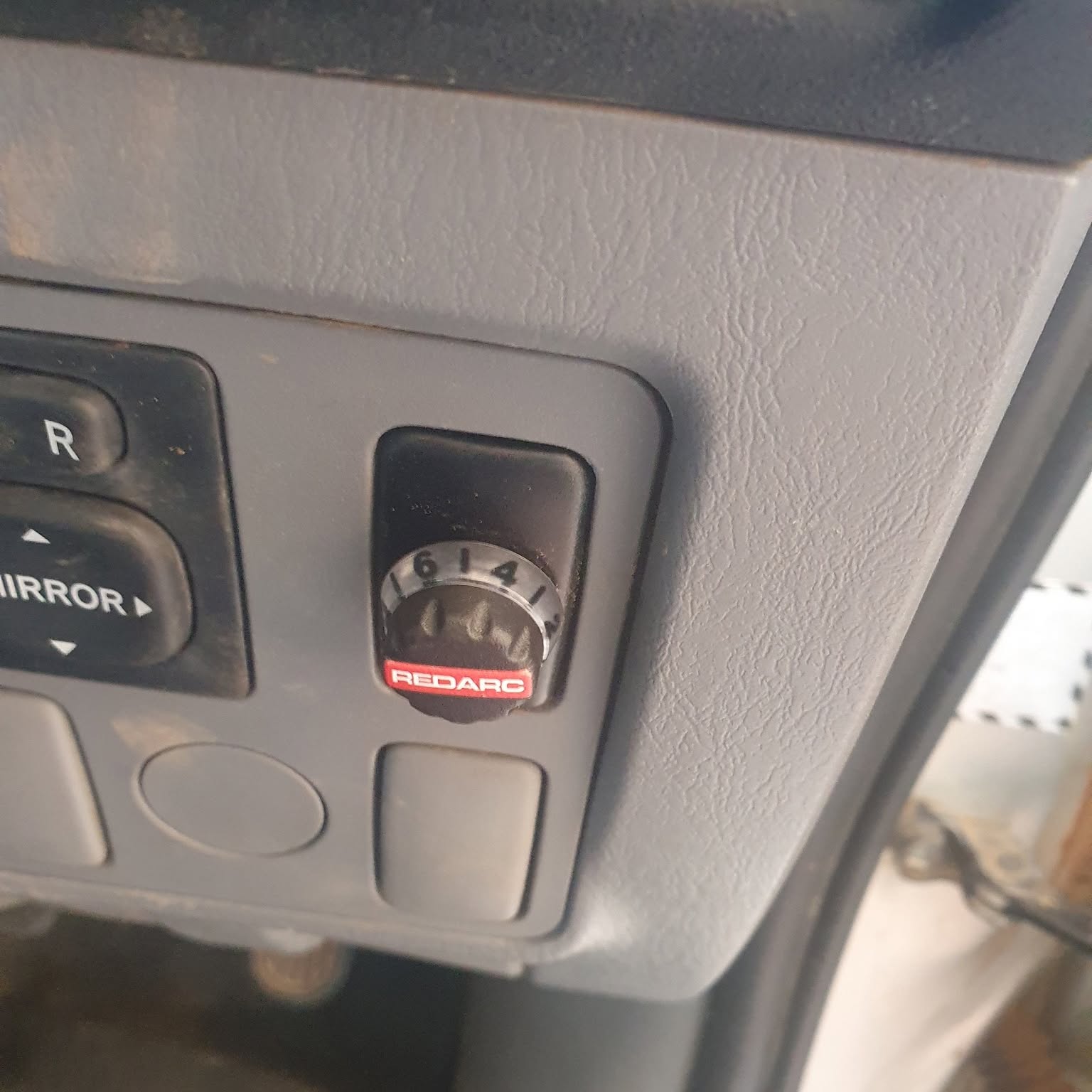 A REDARC brake controller knob fitted flush into a four wheel drive dashboard beside the mirror switches